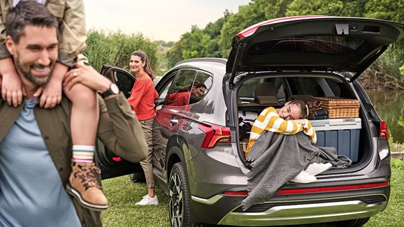 Hyundai bil med bagagerummet fyldt med bagage og en glad familie der holder pause 
