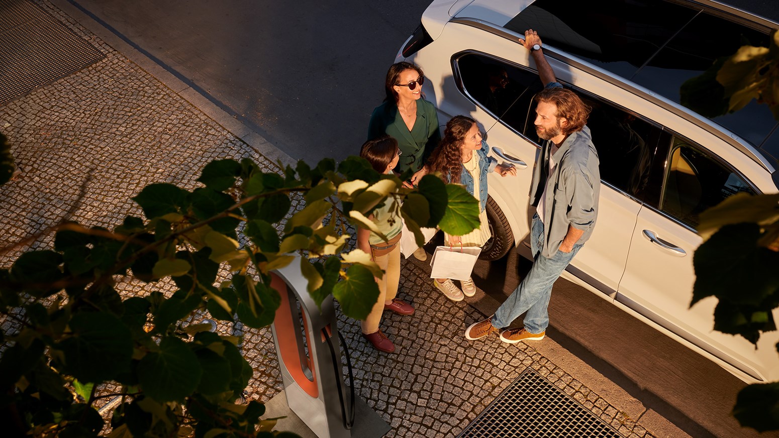 Familie foran Hyundai SANTA FE Plug-in Hybrid der oplades i ladestander