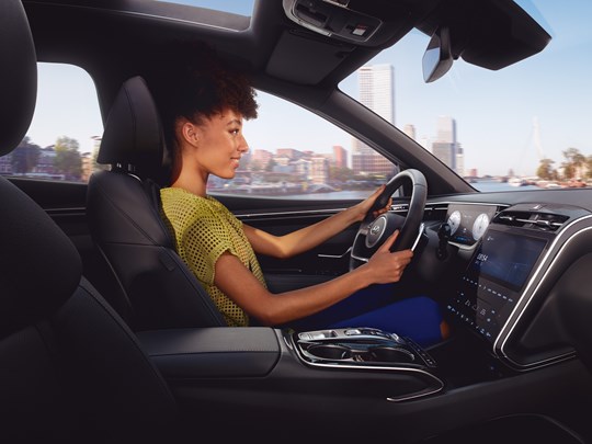 Kvindelig Hyundai-ejer kørende i sin TUCSON Hybrid 