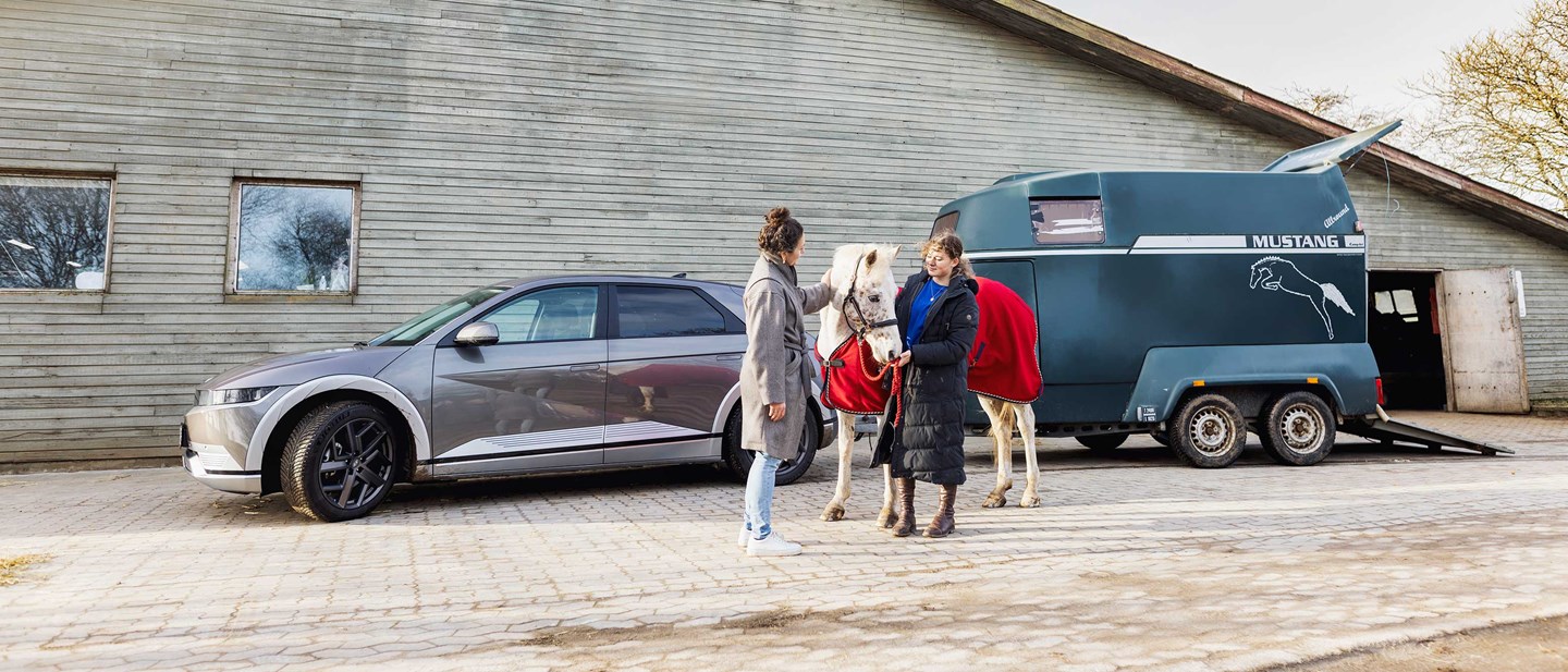 Mor og datter med hest foran Hyundai IONIQ 5 med hestetrailer på anhængertrækket