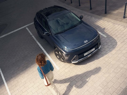 Kvinde går ved siden af parkeret Hyundai KONA set oppefra