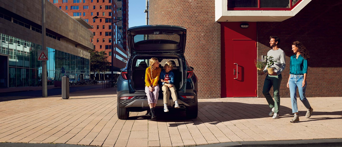 Hyundai familiebil holdende TUCSON i byområde med åben bagagerum