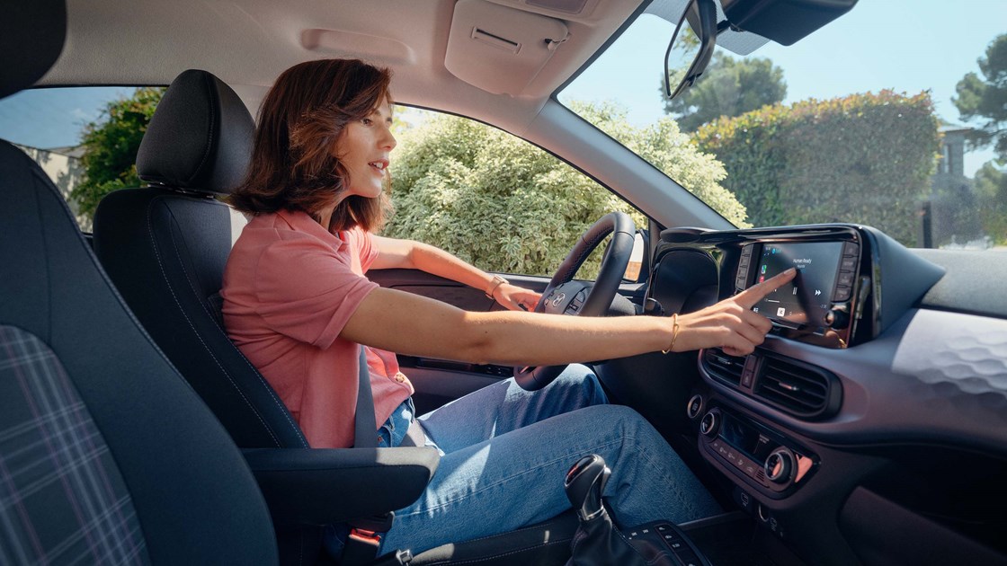 Kvindelig fører benytter touchskærmen i Hyundai i10