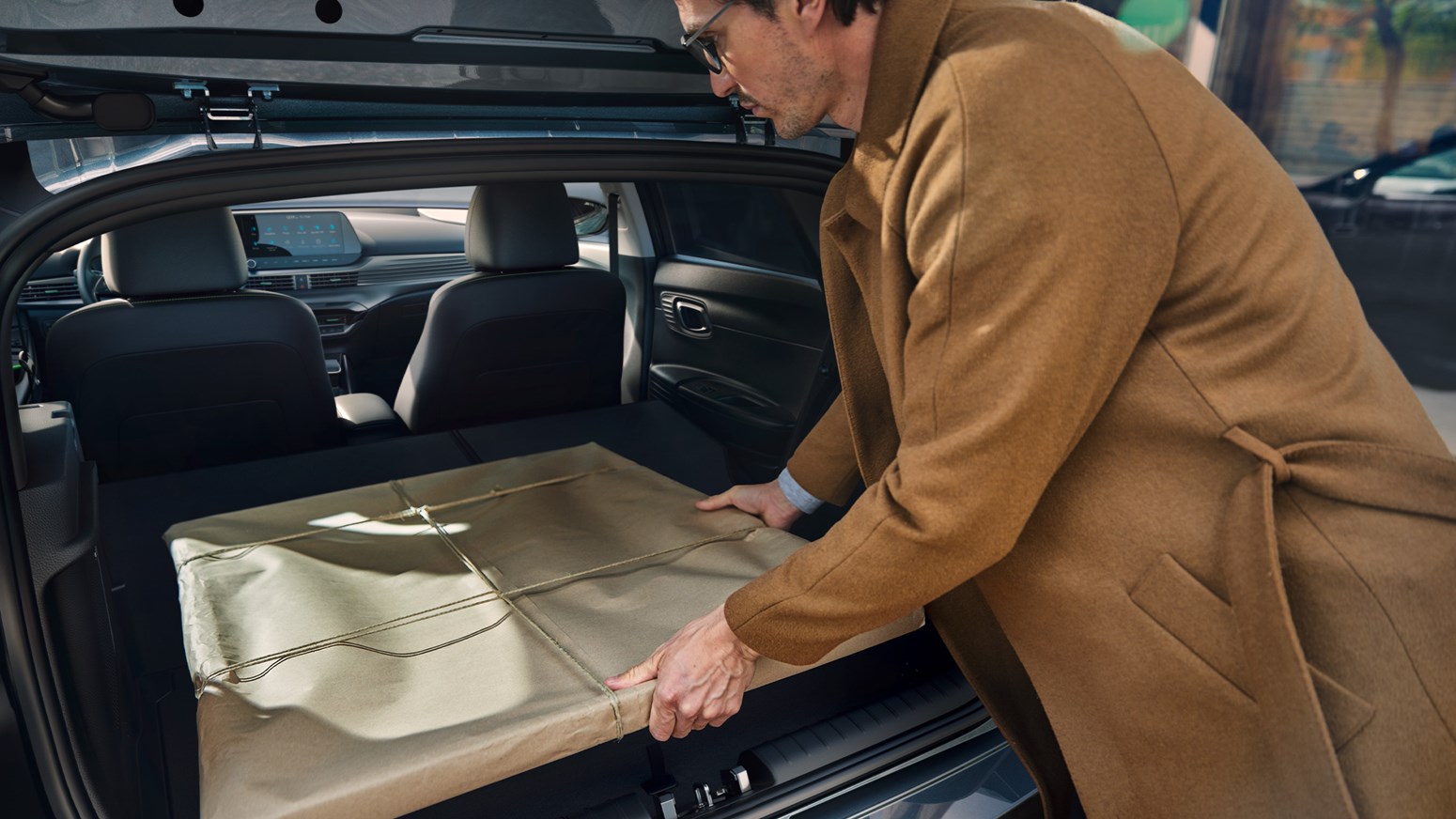 Mand i brun jakke fylder bagagerum i Hyundai i20 med gave