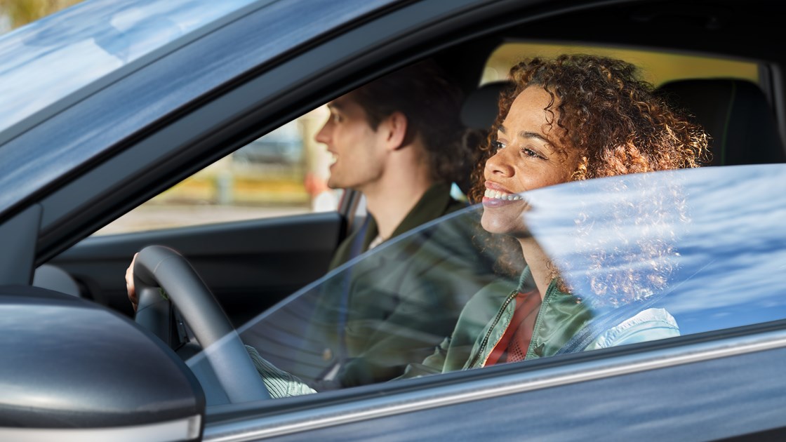 Smilende kvindelig fører med mandlig passager i Hyundai i20 