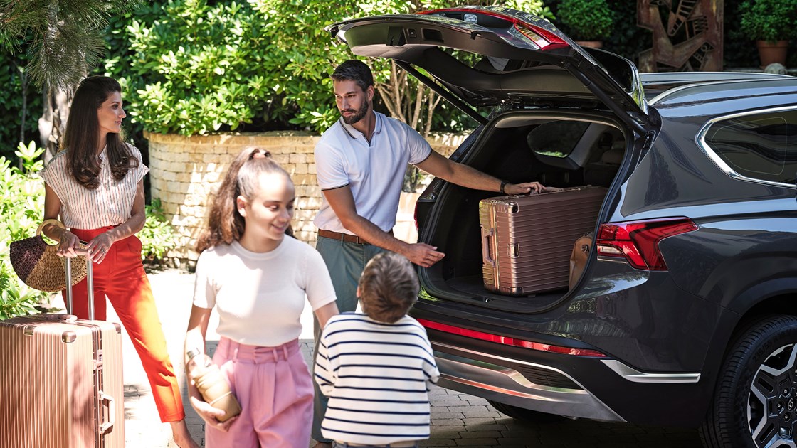 Familie i færd med at pakke bagage i bagagerummet på Hyundai SANTA FE Plug-in Hybrid